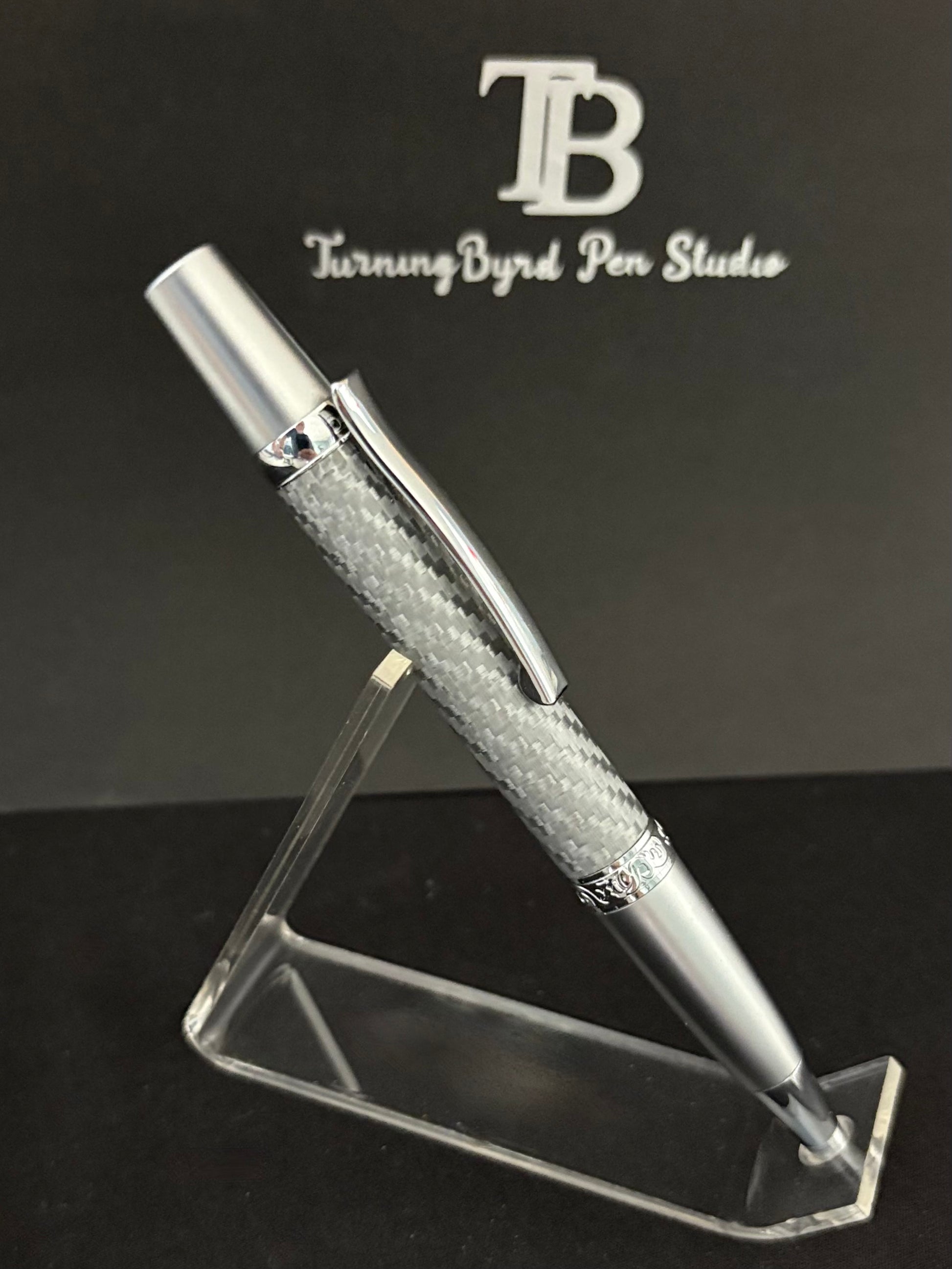 Silver pen on a clear stand with 'Turning Byrd Pen Studio' logo in the background