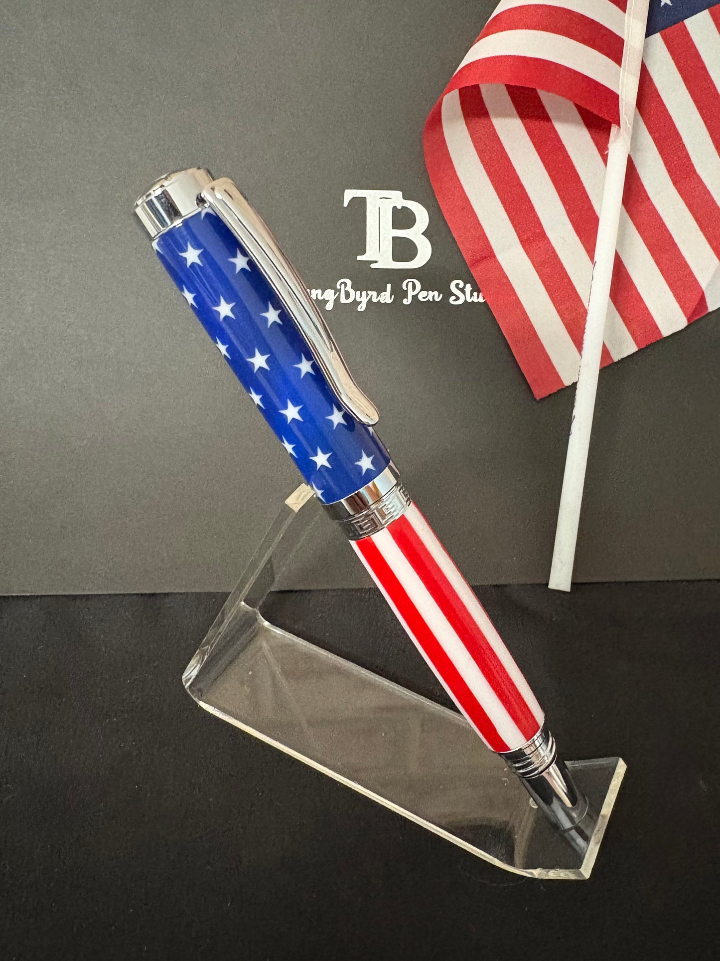 Pen with American flag design on a stand, with an American flag in the background.