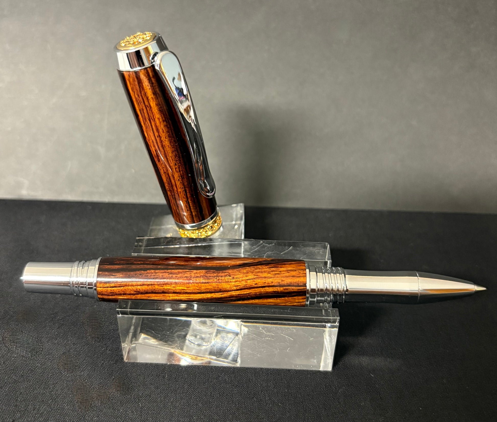 Desert Ironwood pen with silver accents on a clear stand against a gray background