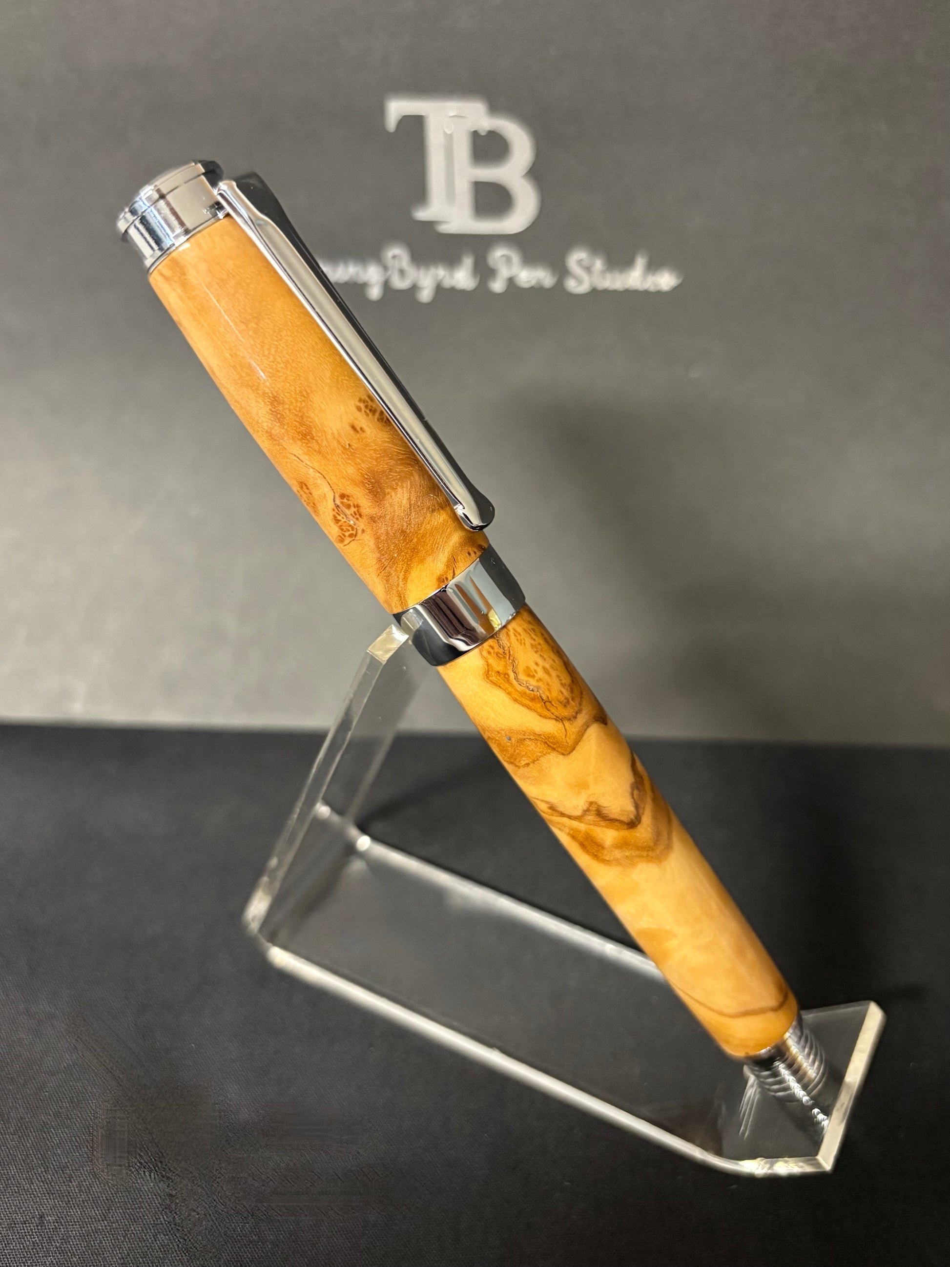 Olive Wood pen with silver accents on a stand against a branded background