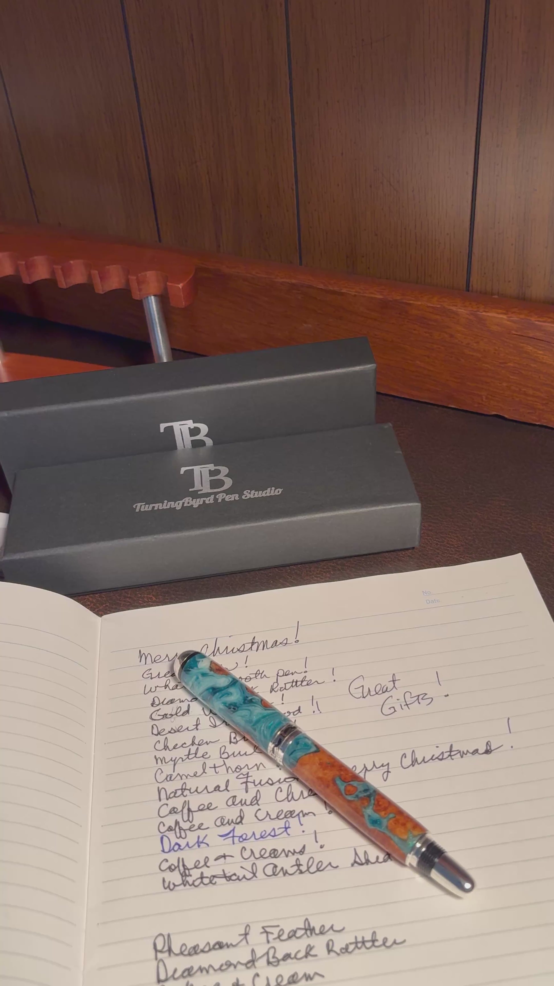 Cherry Burl Wood pen with green and white resin on a clear stand against a gray background with 'TB Turning Byrd Pen Studio' logo.